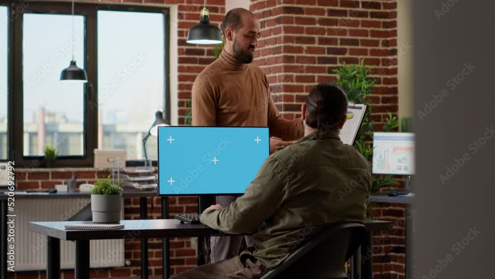 Wall mural company worker looking at greenscreen on computer and business charts, using chroma key display in o