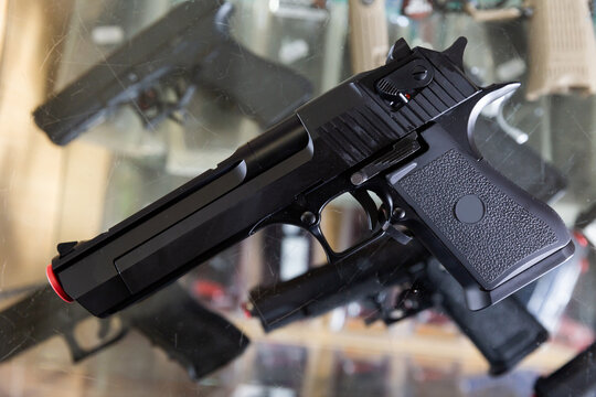 Replica of handgun on showcase in military goods store. Airsoft weapon.