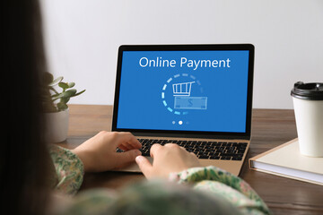 Fototapeta premium Woman using laptop for online payment at wooden table, closeup