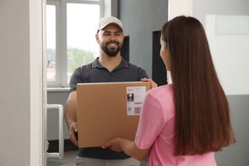 Woman receiving parcel from courier at home