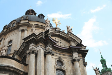 Fototapeta na wymiar LVIV, UKRAINE - MAY 2, 2022: Beautiful Dominican Cathedral against blue sky, low angle view