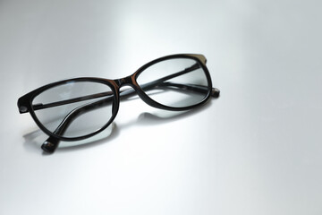 Stylish black eye glasses on white table. Space for text