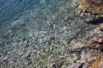 Shallow water with rocky sea bottom as background