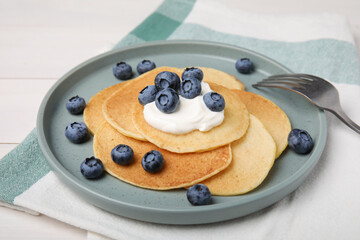 Tasty pancakes with natural yogurt and blueberries on white wooden table