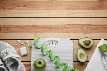 Flat lay composition with bathroom scale and measuring tape on wooden floor, space for text. Weight...