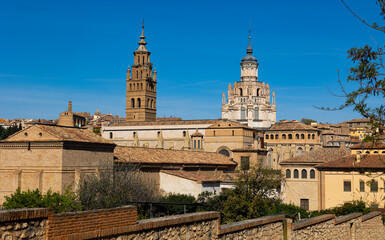 Obraz premium View of bell tower and dome of ancient Roman Catholic Cathedral rising above old residential buildings of historic quarter of Tarazona city against blue cloudless sky on sunny spring day, Spain..