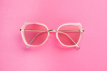 New stylish sunglasses on pink background, top view