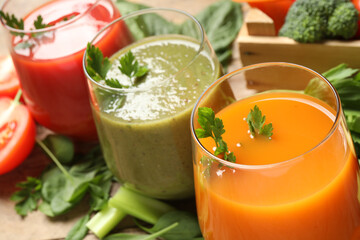 Delicious vegetable juices and fresh ingredients on wooden table, closeup