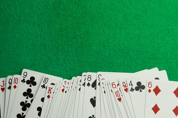 Deck of playing cards on green table, top view. Space for text