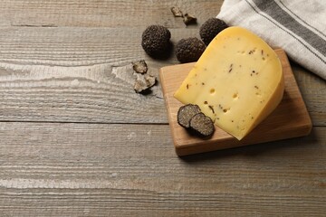 Fototapeta na wymiar Delicious cheese and fresh black truffles on wooden table, above view. Space for text