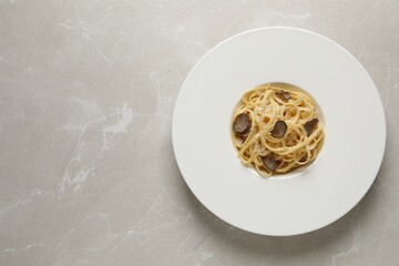 Delicious pasta with truffle slices and cheese on light grey table, top view. Space for text