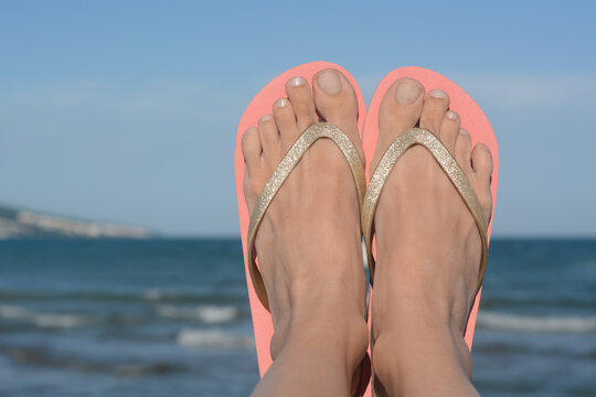 Woman wearing stylish flip flops near sea, closeup