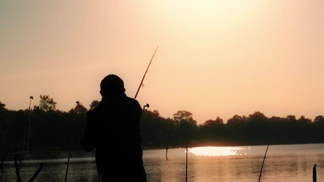 Slow motion video of a man swinging a fishing rod in the morning sun.