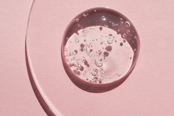 Gels cosmetic product drop in petri dish on pink background, hard shadows