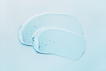 Liquid abstract cosmetic gel smears on blue background. Smear of transparent moisturizing product