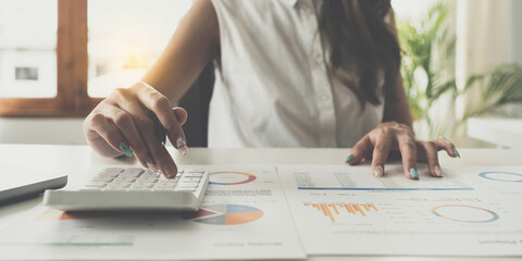 Businesswoman analyzes company's financial system and using calculator.