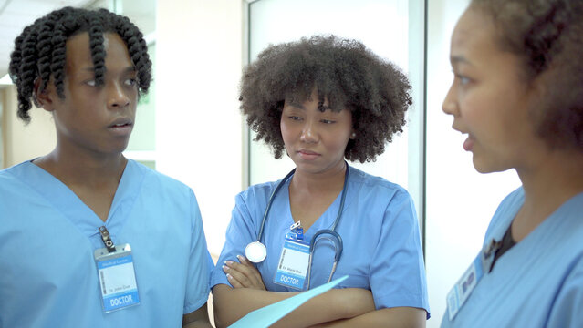 Group of American - African ethnicity medical student or intern doctor in general hospital making a discussion together about symptomatic treatment, happy medical student talking. Healthcare worker.