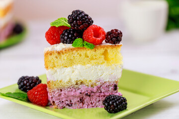 Peace of sponge cake with fresh raspberry and blackberry on wooden table.