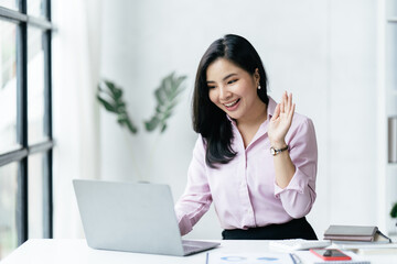 Asian beautiful woman worker talking to the camera video calling video conference with his business partners with face mask.