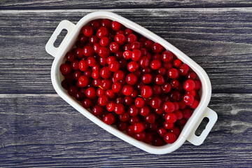 Bowl with red ripe juicy fresh sweet cherries harvest on wooden boards