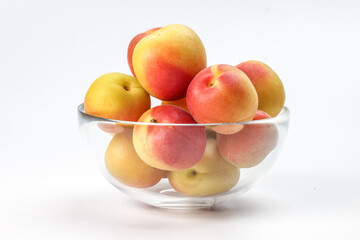 Fresh ripe juicy yellow orange red apricot fruit pile whole cut half slice seed in transparent glass bowl on white background