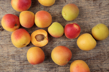 Fresh ripe juicy yellow orange red apricot fruit pile whole cut half slice seed on rustic wood background flat lay top view border frame copy text space