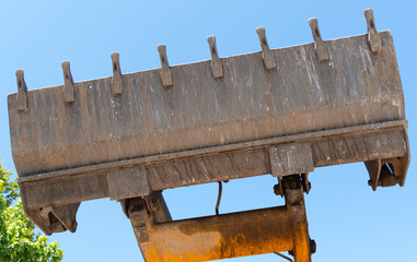 Bulldozer lifting bucket. Excavator bucket against sky.
