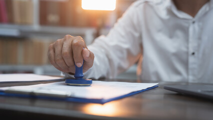 Business person man wearing a white shirt stamp seal into the contract document on the table in the...