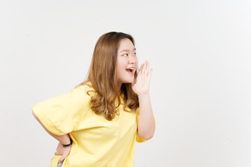 Announcement with hands over mouth of Beautiful Asian Woman wearing yellow T-Shirt Isolated On White