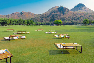 Many dining table set on lawn is surrounded by shady green grass with landscape background. Japanese restaurant tables with mountain background. Enjoy eating outside in green nature. Selective focus.