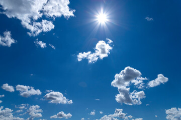 Naklejka na ściany i meble Blue sky with clouds and sun. Bright sun with clouds on blue sky in sunny summer day.