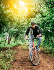 Fototapeta na wymiar A guy riding a bike in the countryside, Person riding a bike in the countryside, Portrait of a guy in cap riding a bike on a country road, Bicyclist person on his bike on a country road forest.