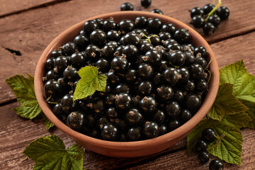 Berries of blackcurrant. Blackcurrant in a bowl isolated on a wooden background. Close-up.
