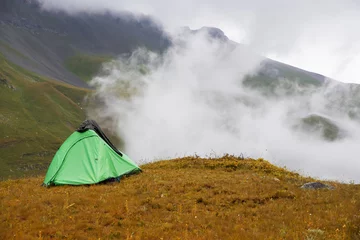 Tissu par mètre Lhotse A tourist tent stands in the mountains against the background of a white cloud.