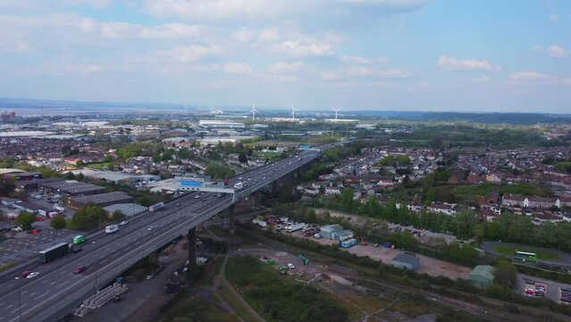 Static drone shot over River Avon facing north with busy M5 motorway full of traffic below, and wind turbines in the distance