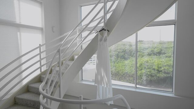 Bride's Wedding dress hanging beautifully in natural light. Dolly outward