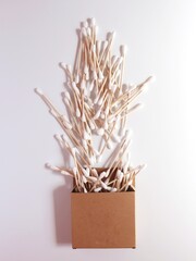 Cotton swabs made of bamboo. falling out of a cardboard box. Top view, white background