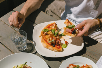 Delicious pizza on summer terrace. Italian cafe menu. Man eating pizza. Close up.