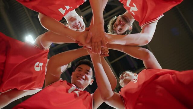 Slow motion, red team of basketball players shouts chants and raising morale before the game, the international basketball championship, view from the lower angle.