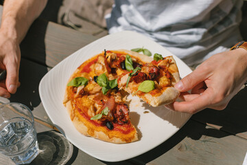 Close up of man eating delicious pizza on summer terrace. Italian cafe menu.