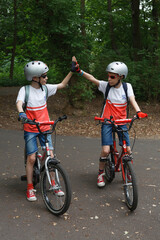 Two boys on bikes giving each other a high five - obrazy, fototapety, plakaty