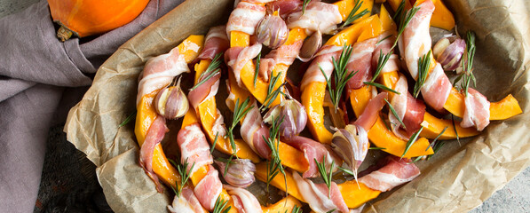 baking sheet with baked pumpkin with bacon on the table