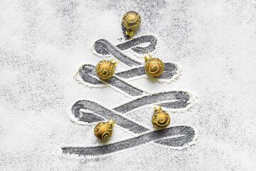 Christmas tree shaped curve on flour surface decorated with baubles