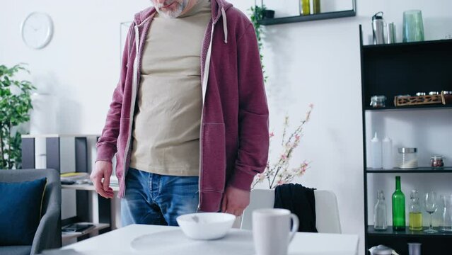 Depressed middle-aged man having breakfast alone, unfulfilled life, loneliness