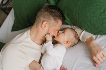 A father with a young son on the bed at home before going to bed.