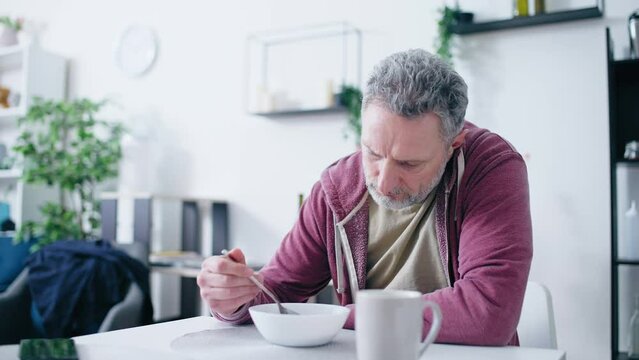 Stressed middle-aged man having no desire to eat, health problems, unsatisfied