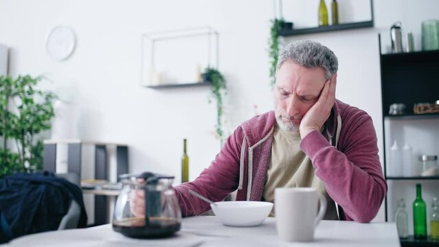 Tired middle-aged man pouring himself coffee, bad morning, unfulfilled life