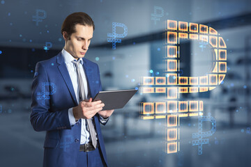 businessman standing with tablet and creative glowing Russian ruble hologram on blurry office interior background. Digital money and online banking concept. Double exposure.