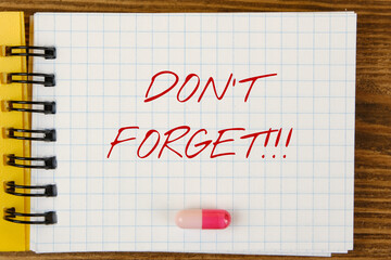 The inscription "don't forget" and a tablet on a notepad sheet. Medication reminder concept.