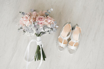 Fototapeta na wymiar Wedding accessories for the bride: a bouquet of pink roses and shoes on the background